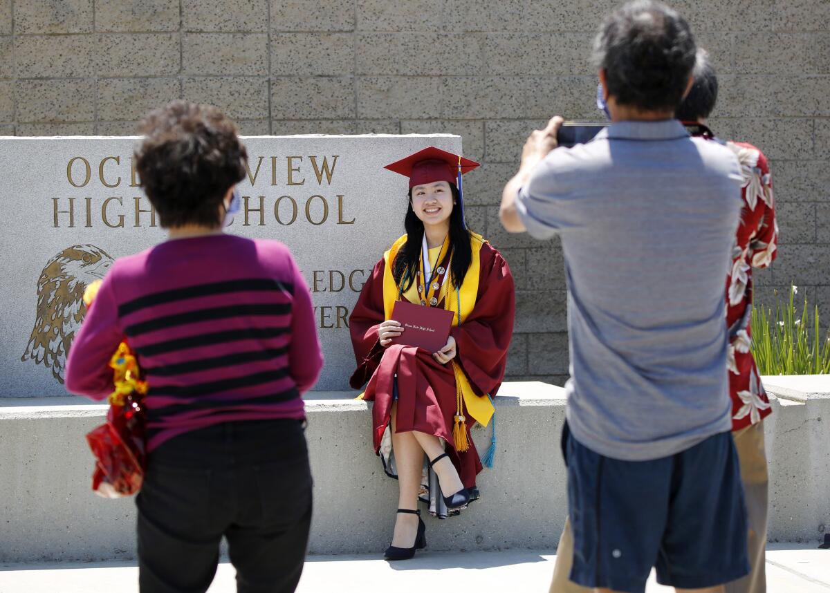 Jordan Ogawa, 17 of Westminster, poses after getting her diploma during a drive-thru graduation at Ocean View.