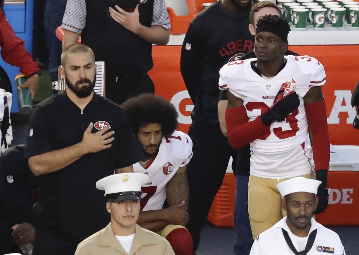 San Francisco quarterback Colin Kaepernick, center, kneels during the national anthem.