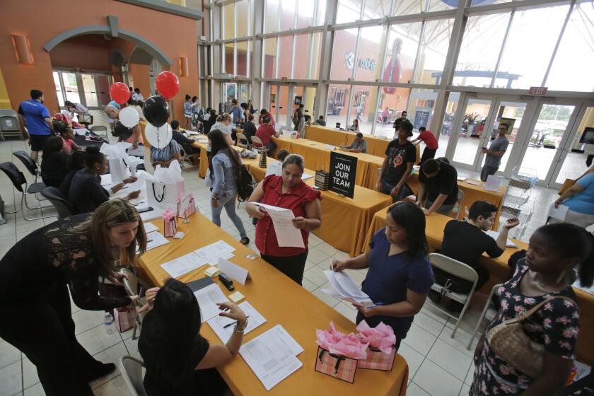 Job applicants fill out and turn in forms during a job fair at Dolphin Mall in Miami on Oct. 6.