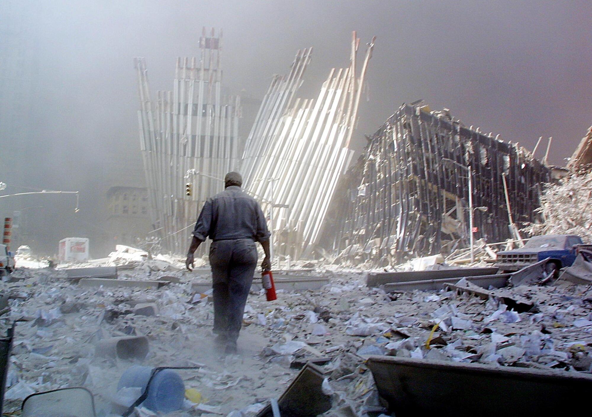 A man carries a fire extinguisher through a street filled with debris
