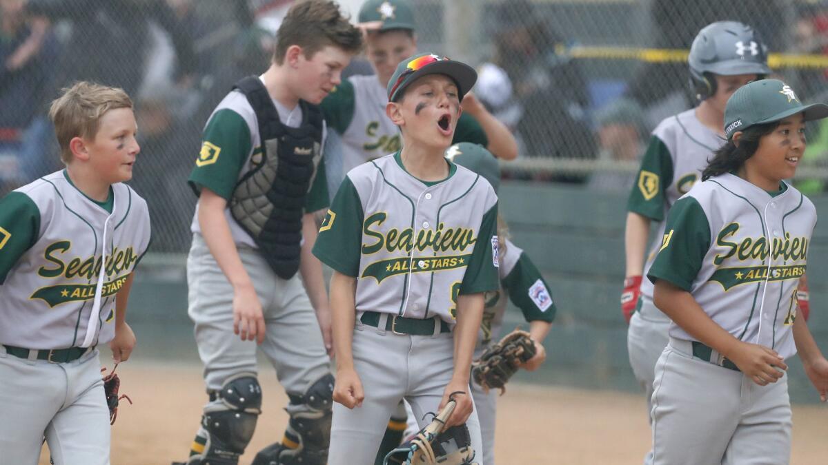 Will Stanley, center, cheers after his team Seaview defeats Costa Mesa American in a Little League District 62 All-Stars Tournament game for 10- and 11-year-olds on Tuesday at Fountain Valley Sports Park.