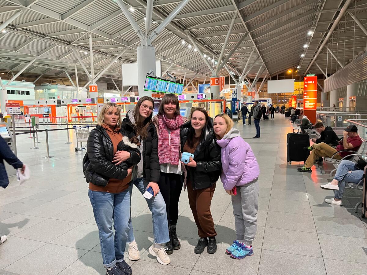 A group of five women pose for a photo in an airport terminal