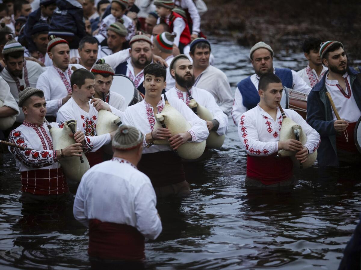 Men play bagpipes and drums as they wade into the cold Tundzha River to celebrate Epiphany, in the town of Kalofer, Bulgaria, Saturday, Jan. 6, 2024. The legend goes that the person who retrieves the wooden cross from the river will be freed from evil spirits and will be healthy throughout the year. Epiphany marks the end of the 12 days of Christmas, but not all Orthodox Christian churches celebrate it on the same day. (AP Photo/Valentina Petrova)