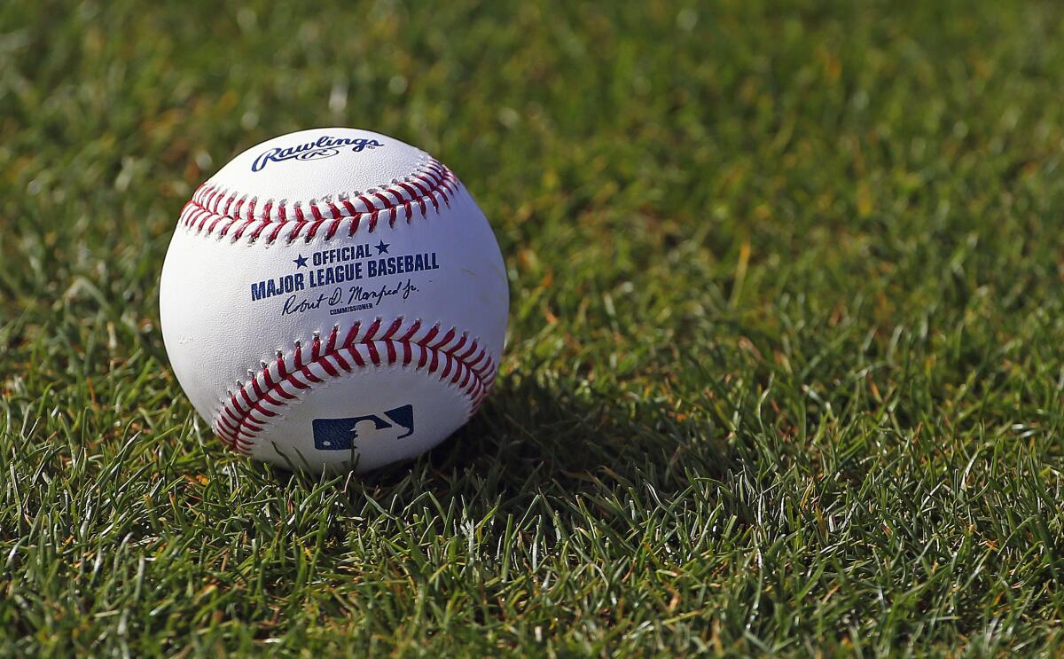 A baseball is shown on the grass at the Cincinnati Reds' spring training facility in Goodyear, Ariz.