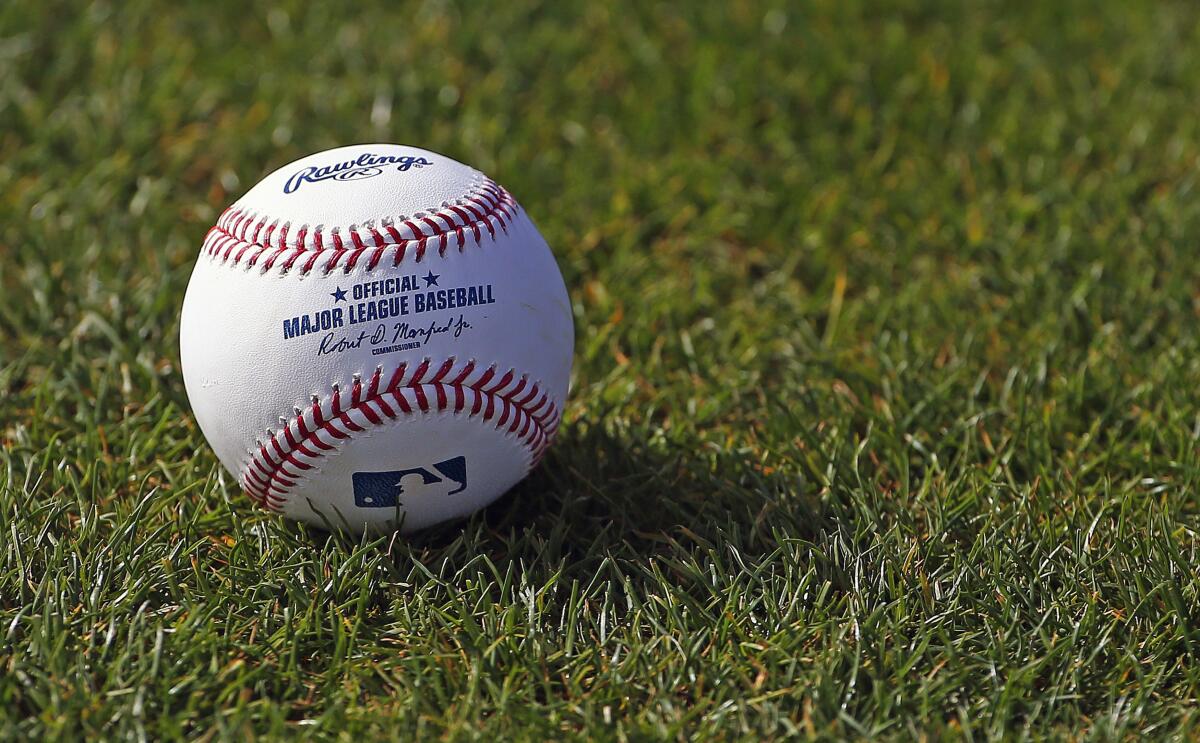 A baseball rests on the grass at the Cincinnati Reds baseball spring training facility in Goodyear, Ariz.