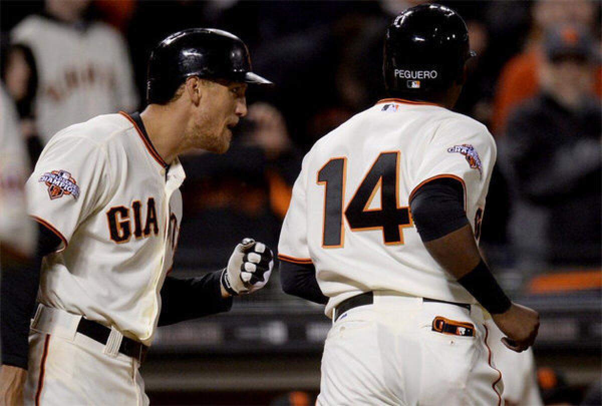 San Francisco Giants' Hunter Pence congratulates Francisco Peguero (14) after Peguero scored the game-tying run on a sacrifice fly off the bat of Pablo Sandoval in the seventh inning.