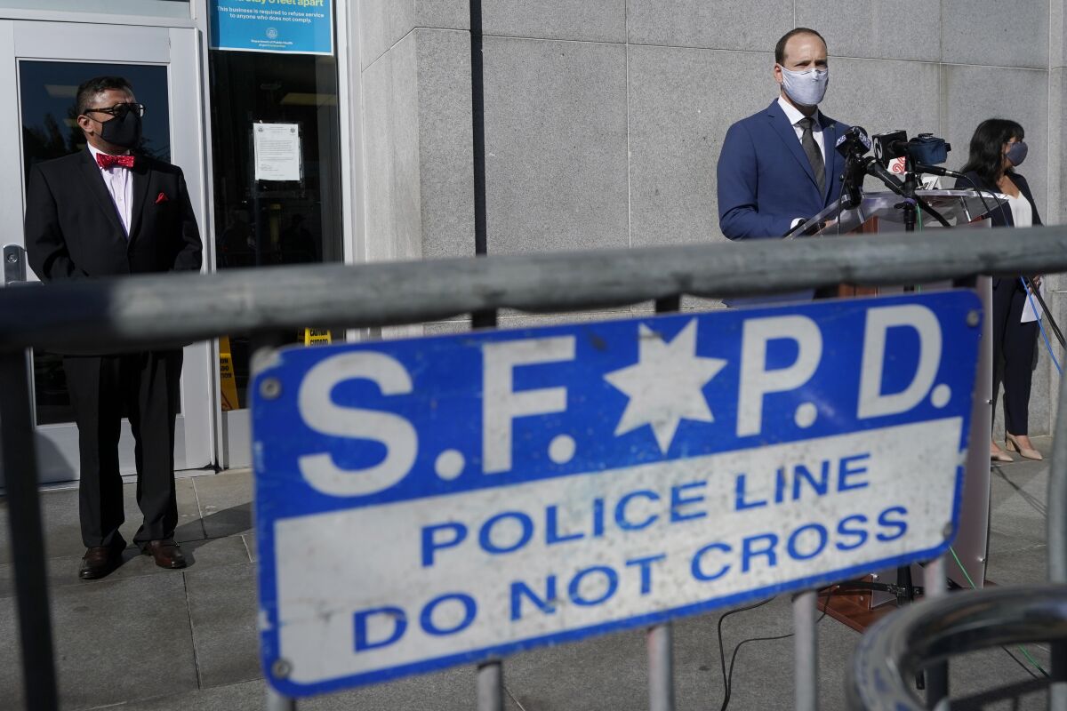 San Francisco D.A. Chesa Boudin behind a sign saying "SFPD police line do not cross"