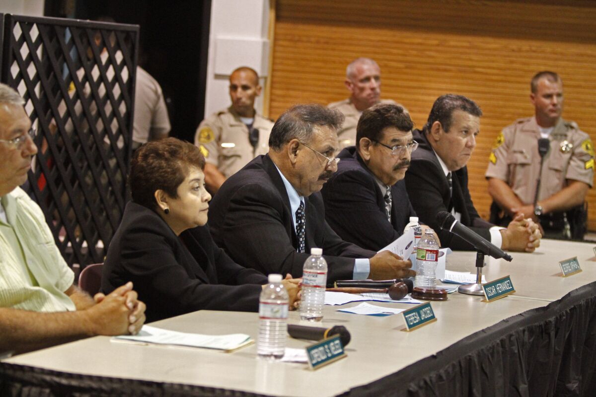 Los Angeles County Sheriff deputies stand near the Bell City Council during a meeting filled with angry citizens upset with the high salaries paid to the members.