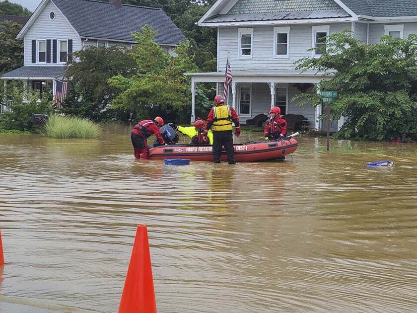Emergency personnel and first responders work to help residents get on a raft in a flooded street