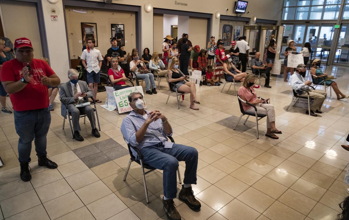 Riverside County residents watch video monitors of an emergency Riverside County Board of Supervisors meeting last month.