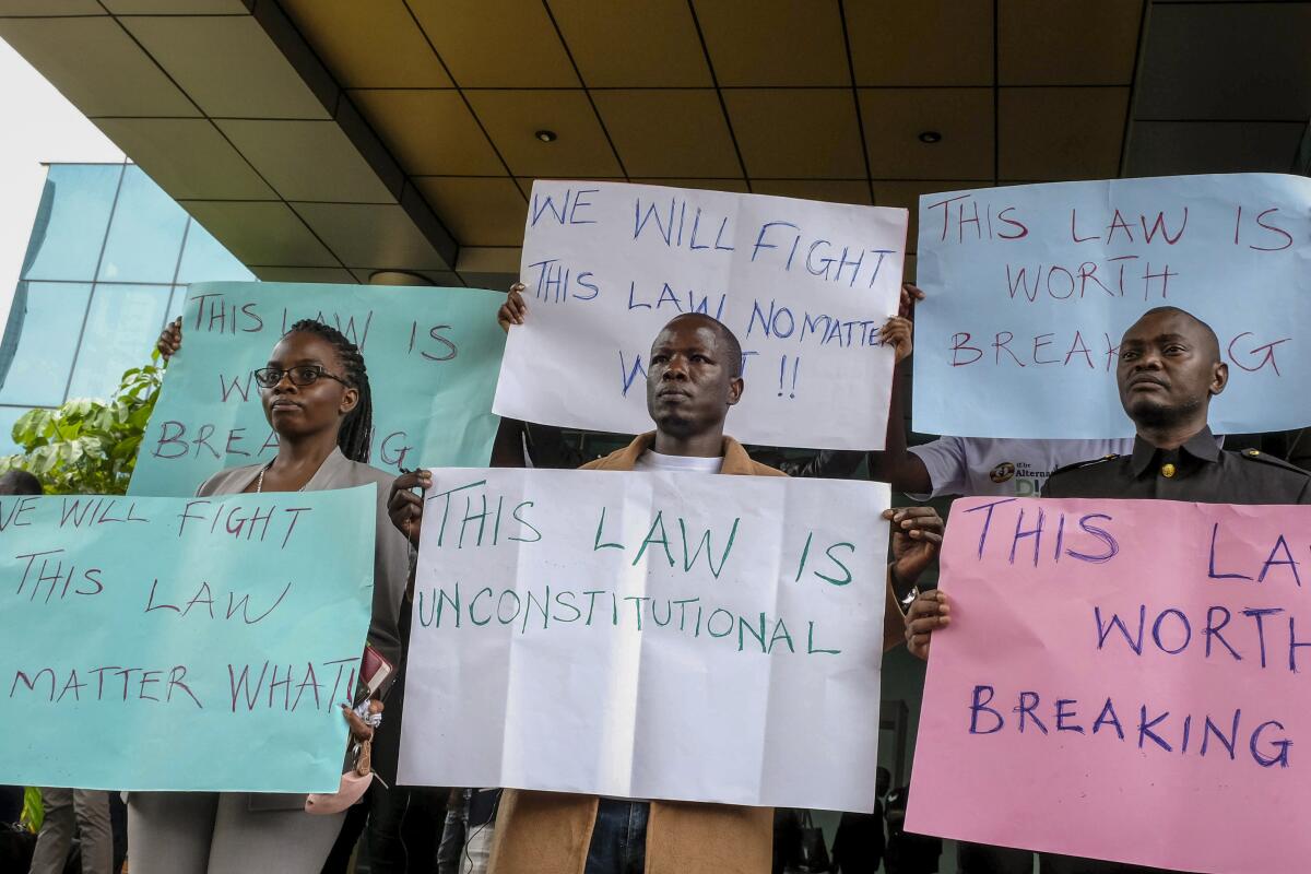 Digital activists hold placards as they demonstrate after submitting a legal petition against controversial new legislation criminalizing some internet activity, at the constitutional court in Kampala, Uganda, Monday, Oct. 17, 2022. The petition to the constitutional court argues that the description of computer-related crimes in the bill enacted with President Yoweri Museveni's signature last week violates the right to freedom of expression and criminalizes some digital work, including investigative journalism. (AP Photo/Hajarah Nalwadda)