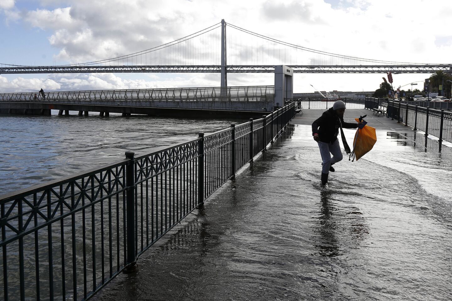 A woman walks through water from a king tide that flooded onto the Embarcadero in San Francisco on Wednesday.