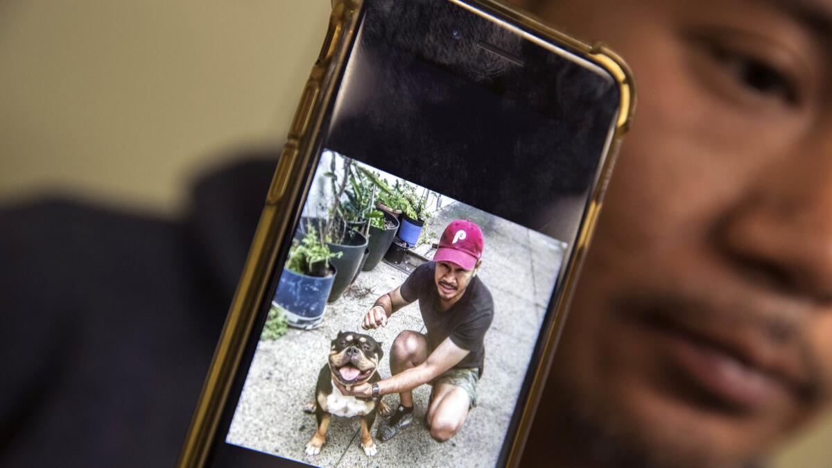 Cambodian refugee Posda Tuot holds a smartphone image of his cousin Nak Kim "Rickie" Chhoeun, pictured with his dog Sashimi. Chhouen was detained after going into a federal building in L.A. for his usual immigration check.