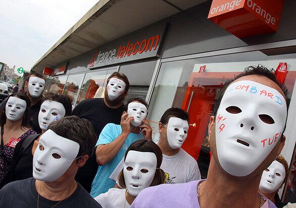 France Telecom employees wear masks in front of one of the company's outlets after unions called for two days of strike and protests. The company has undergone major restructuring that, according to the unions, has left workers stressed and demoralized.