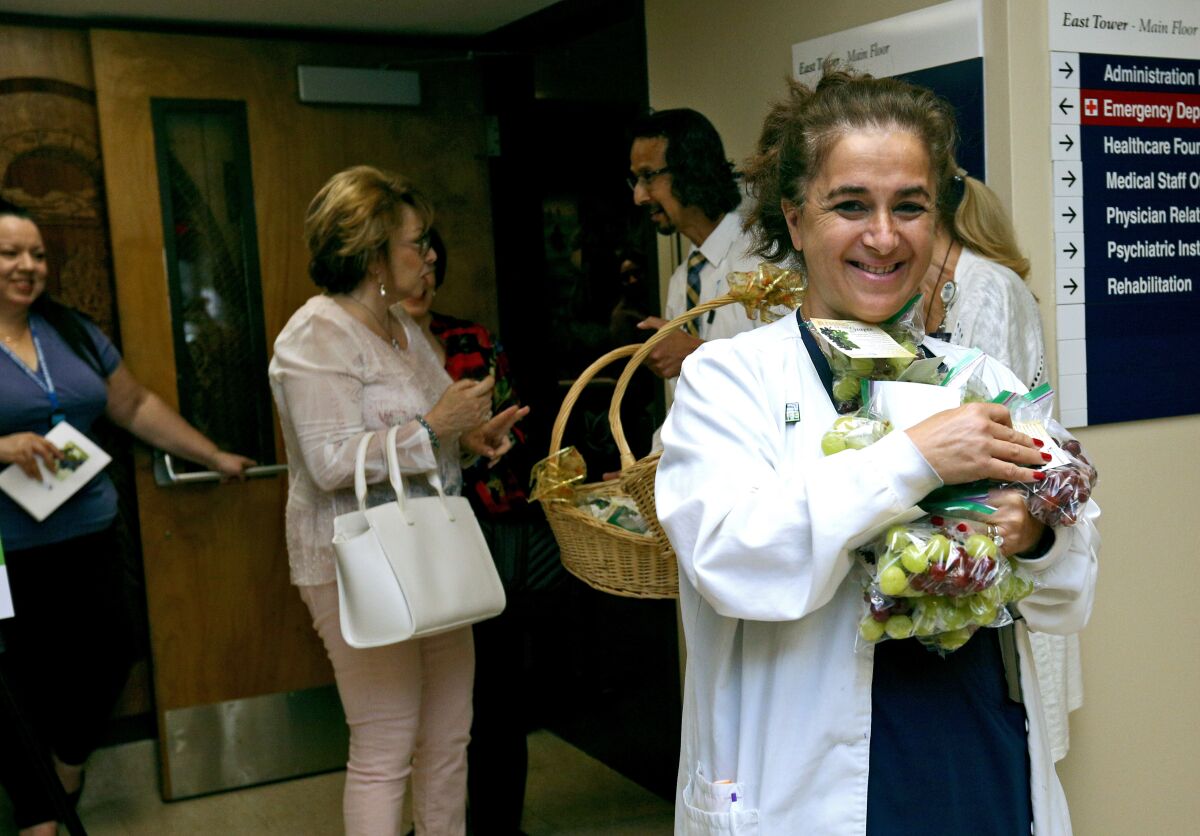 Fiklor Izanian, a registered nurse, takes grapes for other employees after the Blessing of the Grapes ceremony at Adventist Health Glendale on Wednesday. The blessing of the grapes is an Armenian harvest-time celebration. Also, the local hospital was recently ranked in 10th place out of more than 130 hospitals in the Los Angeles area.