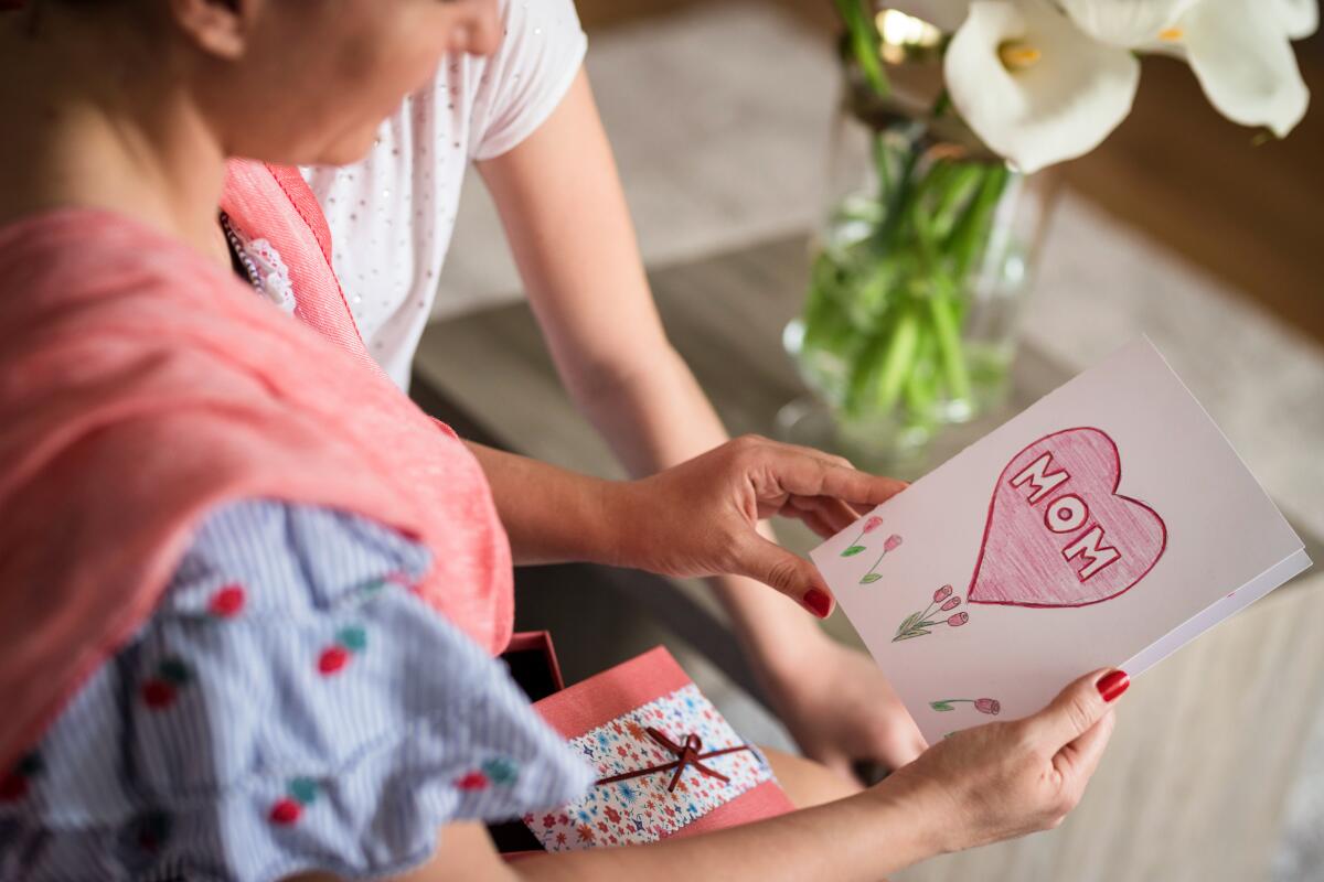 A woman holds a hand-drawn Mother's Day card.