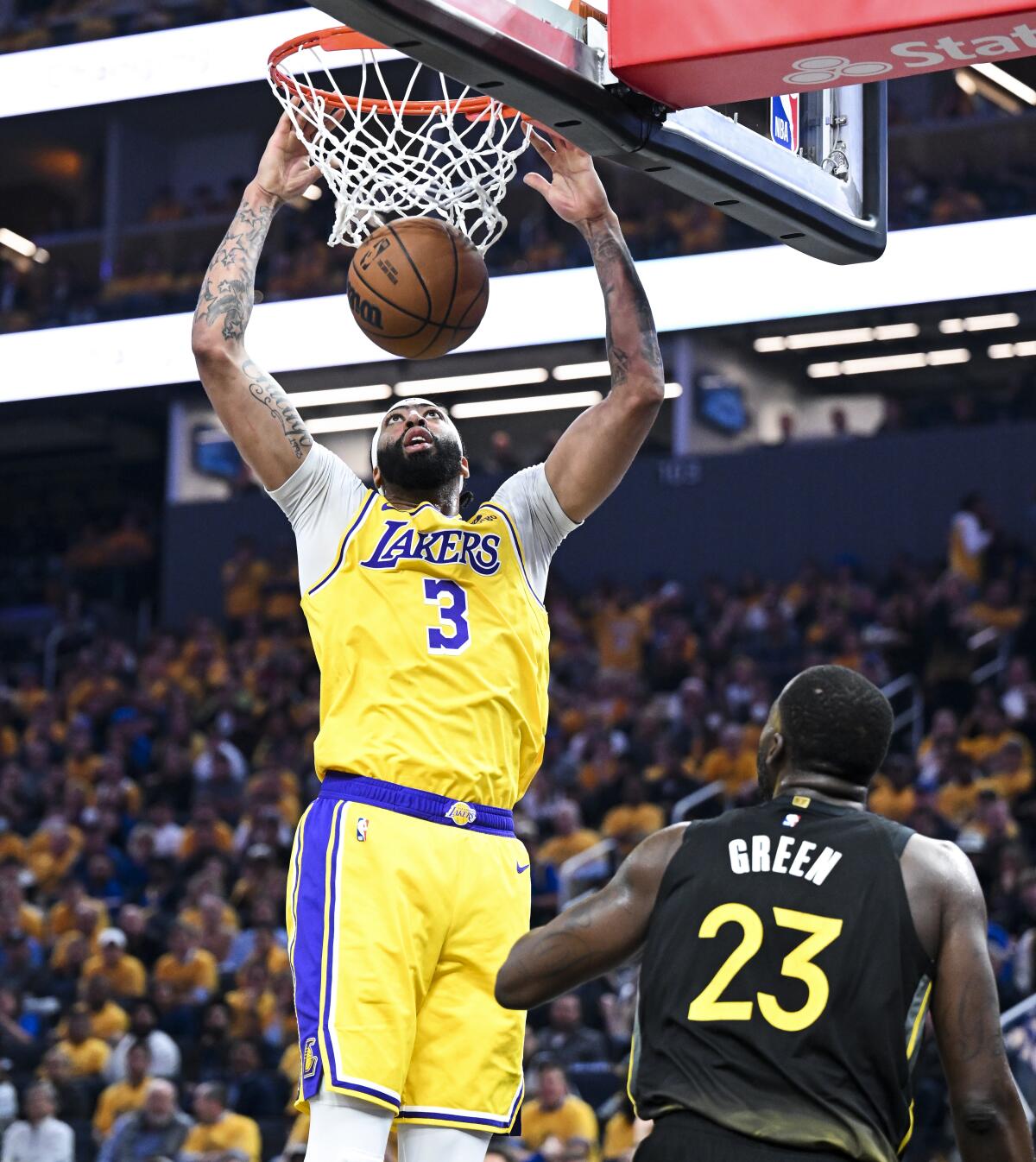Lakers forward Anthony Davis dunks the ball over Warriors forward Draymond Green.