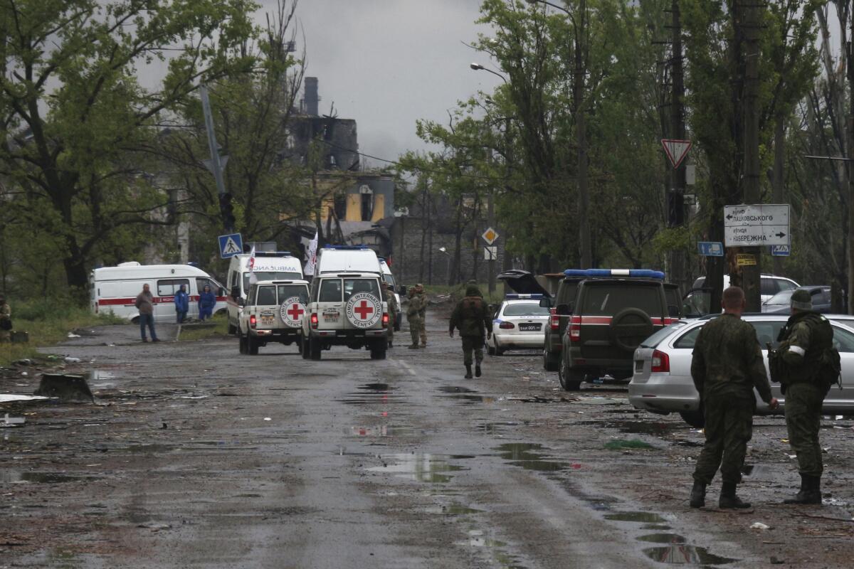 International Red Cross vehicles in Mariupol, Ukraine, near people walking