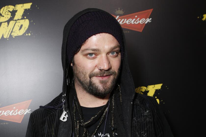 Bam Margera wearing black beanie and black hoodie, smiling with short beard