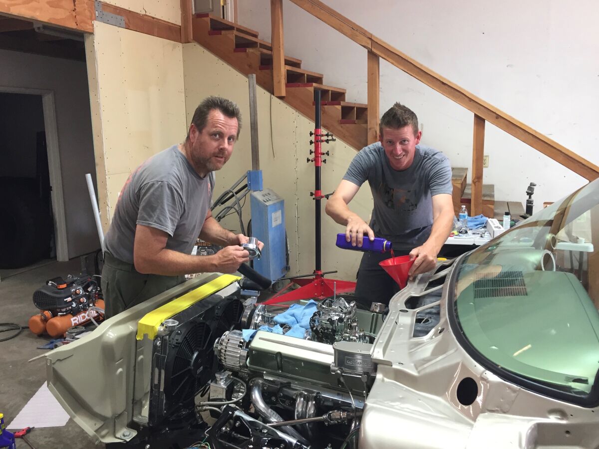Ken Vossen and friend Jesse Lindberg stand over an open car engine.