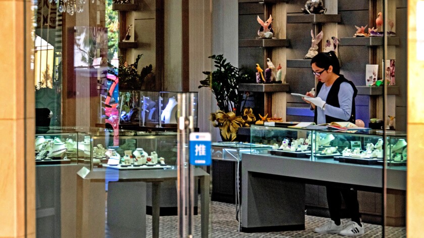 A staff member at House of Italy Jewelry in the San Gabriel Square shopping center occupies herself with bookkeeping as she watches over the vacant shop floor.