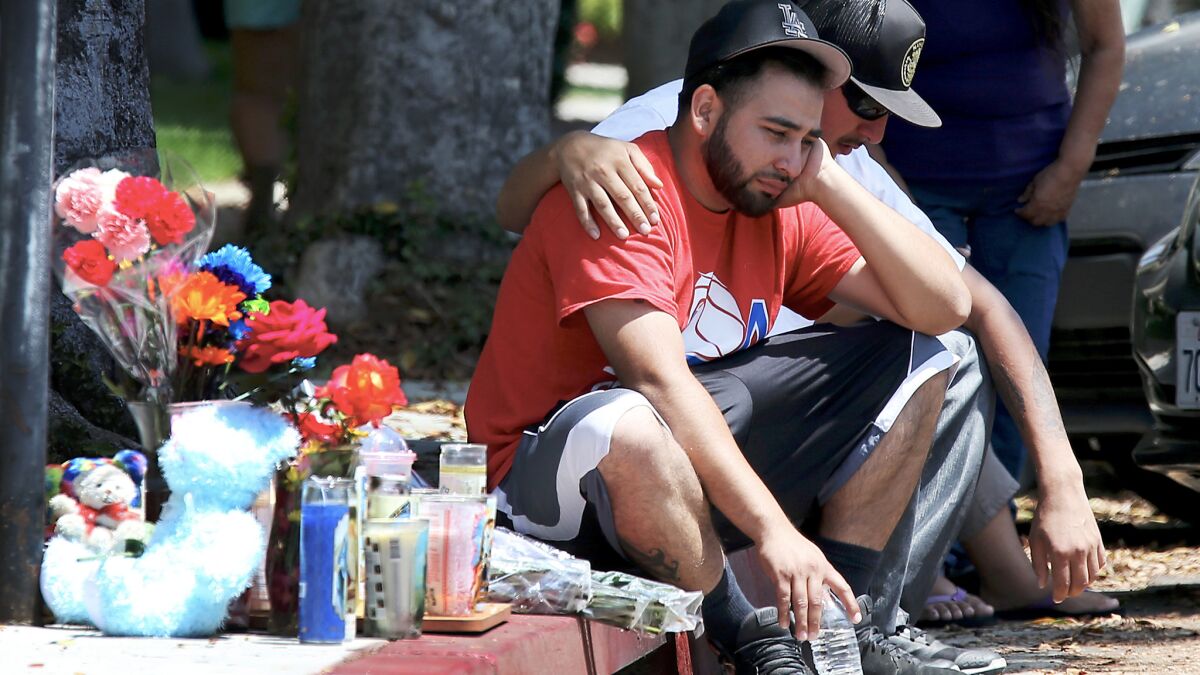 Relatives and friends pay condolences to Luis Anaya, left, whose 4-year-old daughter was shot and killed along with her mother at the intersection of 9th Street and Locust Avenue in Long Beach on Saturday night.