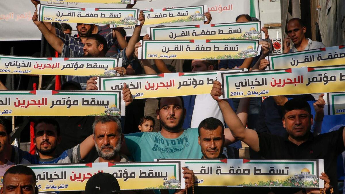 Palestinians in Gaza City hold banners on June 25, 2019, denouncing the U.S.-led Peace to Prosperity conference in Bahrain.