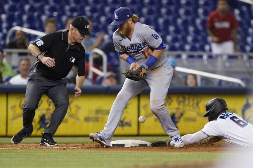 Miami Marlins' Starling Marte slides into third base as Los Angeles Dodgers third baseman Justin Turner (10) is unable to hang on to the throw during the 10th inning of a baseball game, Tuesday, July 6, 2021, in Miami. The Marlins won 2-1 in 10 innings as Marte scored from second on a wild pitch and a throwing error. (AP Photo/Wilfredo Lee)