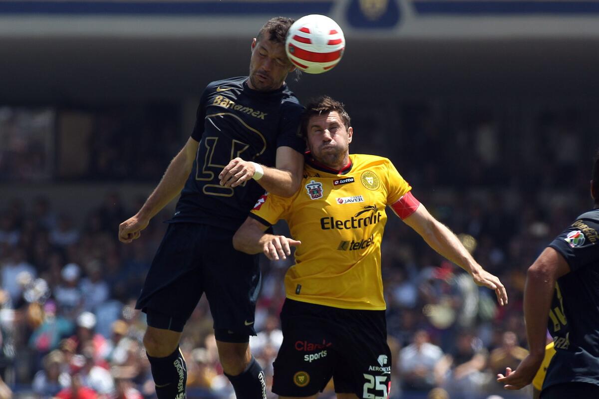 El jugador de Pumas Dante López (i) y Leandro Cufré (d) de Leones Negros disputan el balón durante un partido de la jornada 12 del Torneo Clausura.