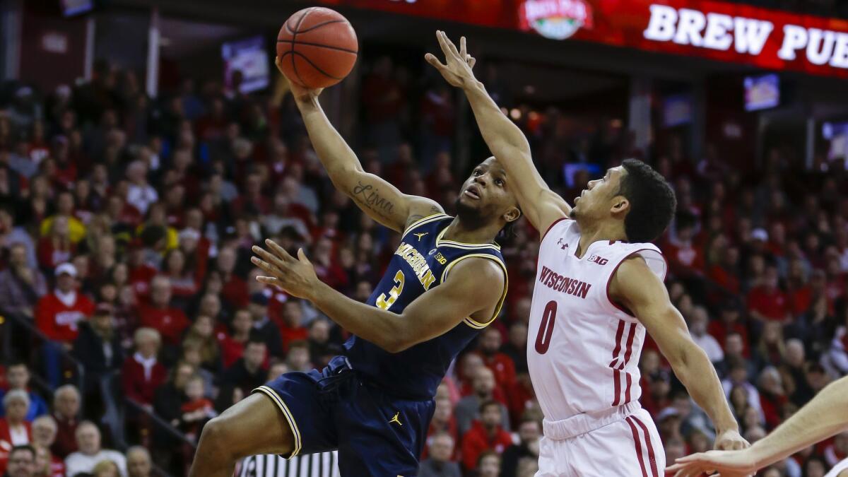 Michigan's Zavier Simpson (3) shoots against Wisconsin's D'Mitrik Trice (0) during the first half.