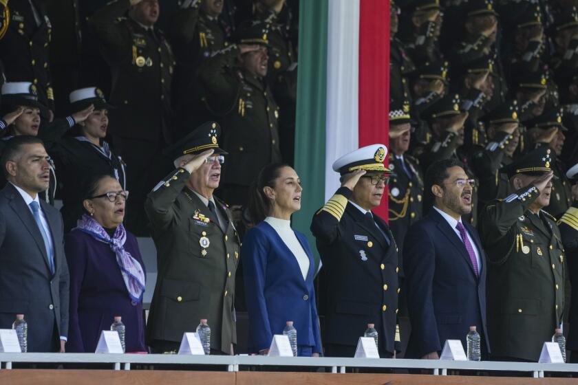 La presidenta mexicana Claudia Sheinbaum, en el centro; el ministro de Defensa, general Ricardo Trevilla Trejo, a la izquierda, y el secretario de Marina, almirante Raymundo Pedro Morales, cantan el himno nacional durante una revisión de tropas en el Campo Marte en la Ciudad de México, el jueves 3 de octubre de 2024. (AP Foto/Fernando Llano)