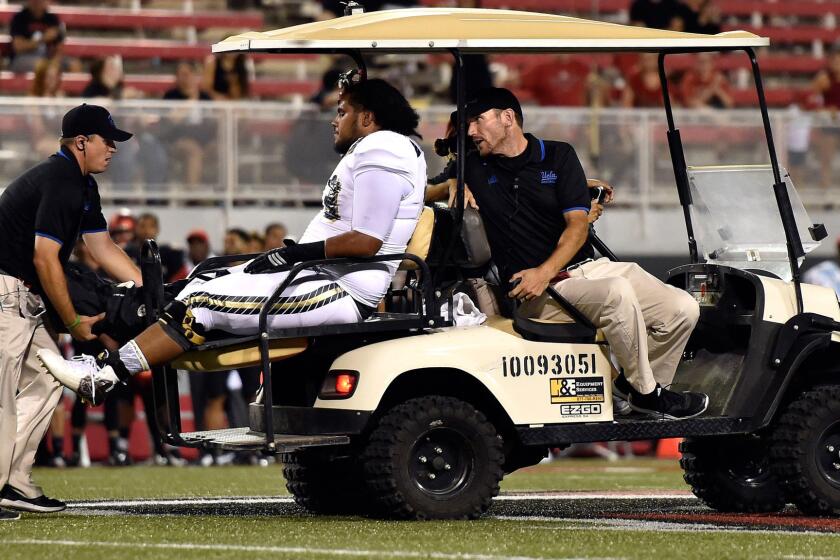 Bruins offensive lineman Tevita Halalilo is driven away after suffering an injury in the final minute of a 37-3 win over UNLV on Saturday night.