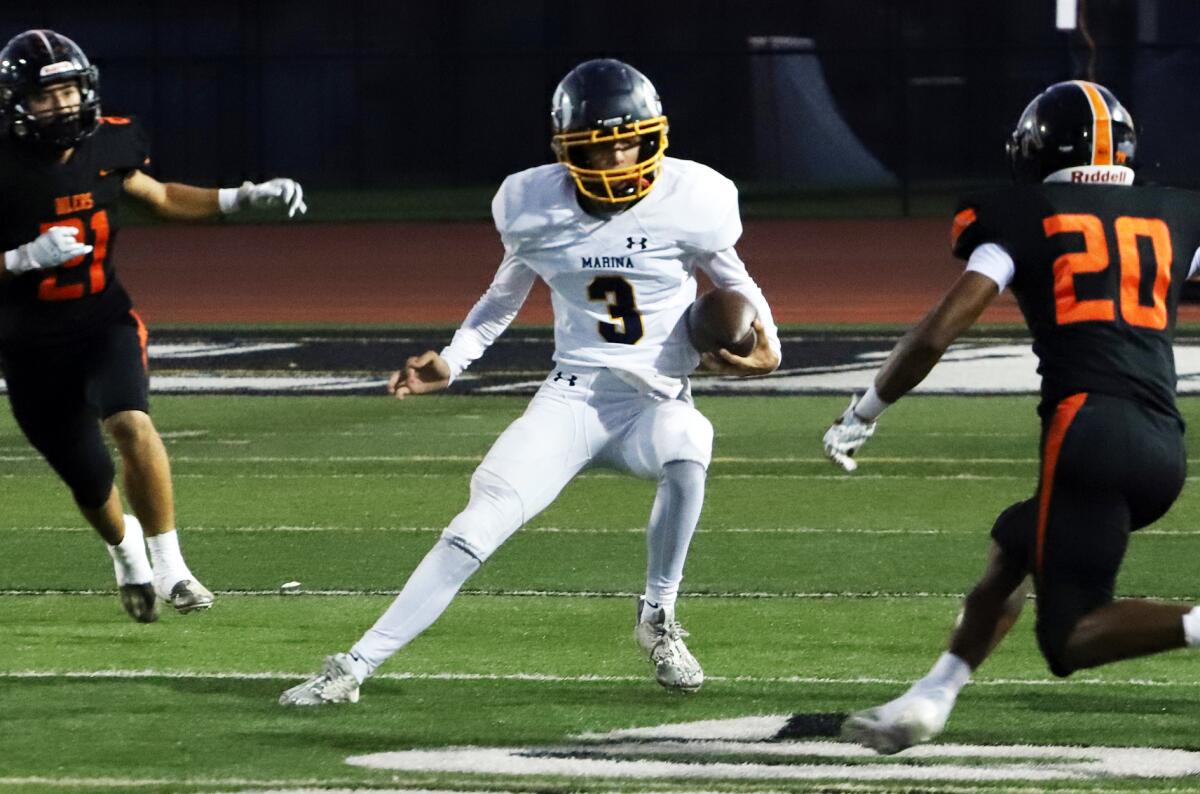 Marina quarterback Garrett Hunnicutt (3) tries to scramble around Huntington Beach's defense on Thursday.
