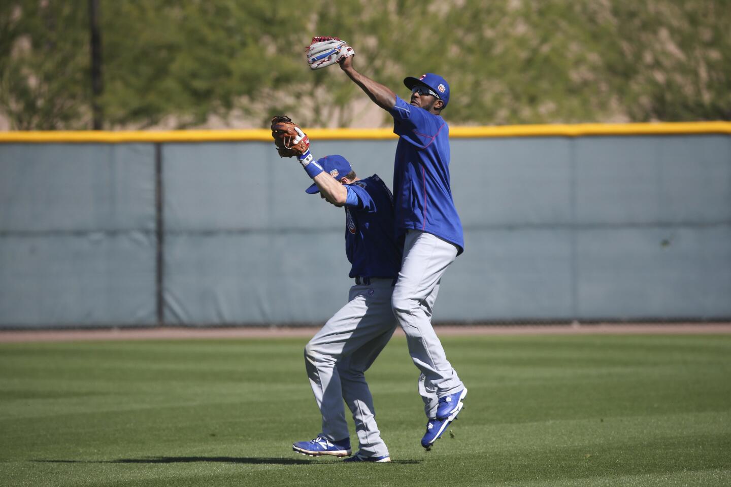 Dexter Fowler attempts to catch a fly ball caught by Ben Zobrist during spring training at Sloan Park Friday, Feb. 26, 2016, in Mesa, Ariz.