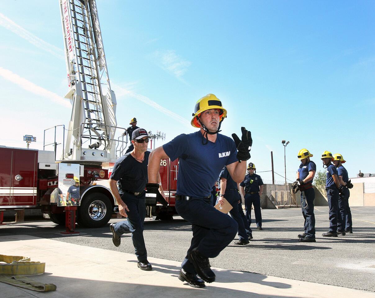 Fire recruit Blikian runs to the last task of a timed course with his trainer running behind him on the first day of recruit training for the Glendale Fire Department at the department training grounds in Glendale on Monday, March 17, 2014. (Tim Berger/Staff Photographer)