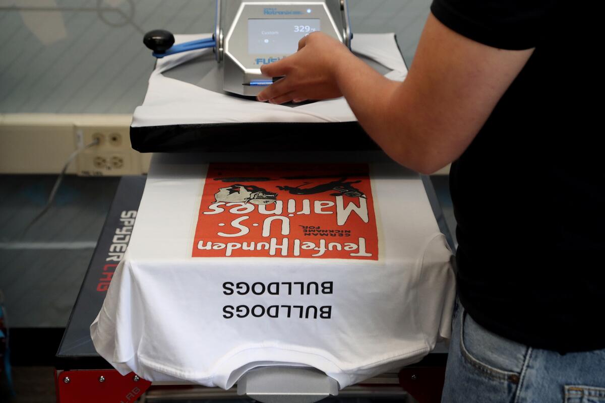 A student prints on a T-shirt using a direct to garment printer.