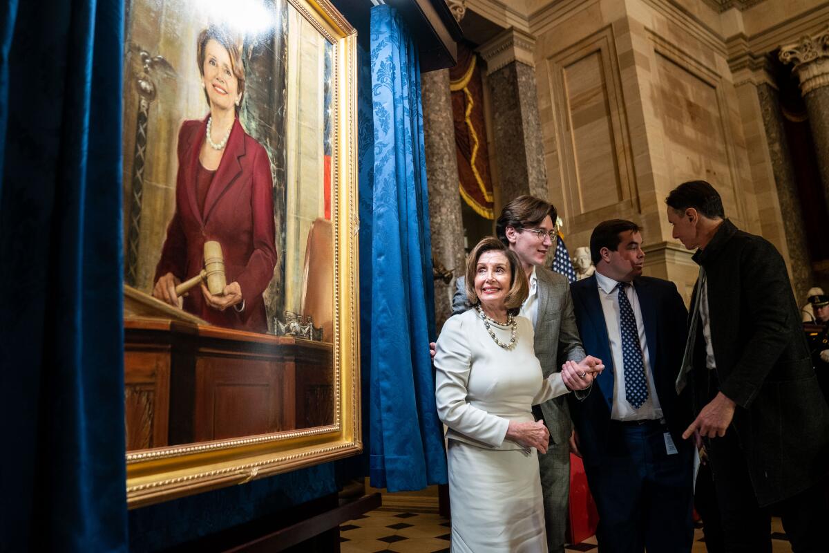 Nancy Pelosi stands near a painting of her in the U.S. Capitol.
