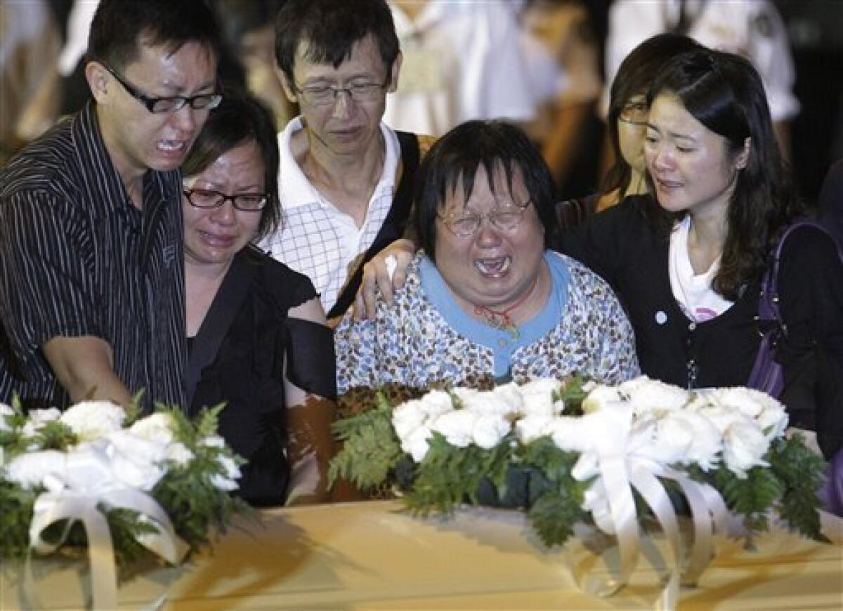 Relatives weep as they lay wreaths on a coffin of a Hong Kong tourist who was killed in Monday's hostage standoff in the Philippines as the bodies of the slain victims arrive at the Hong Kong airport, Wednesday, Aug. 25, 2010. A charter flight brought the bodies of eight victims of the bus hijacking in the Philippines back home to Hong Kong on Wednesday. (AP Photo/Kin Cheung)