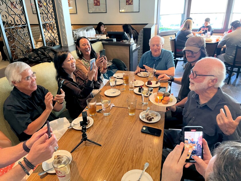 Nick Ut, left, Anh Do, center, and Naja Lockwood, right, take cellphone photos of David Hume Kennerly.