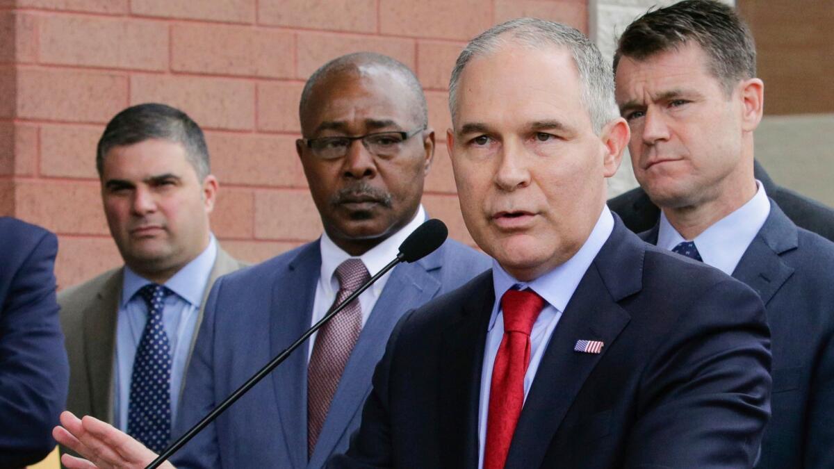 Environmental Protection Agency head Scott Pruitt speaks at a news conference in East Chicago, Ind., in 2017. Security chief Pasquale "Nino" Perrotta, left, is one of two aides whose departures were announced Tuesday.