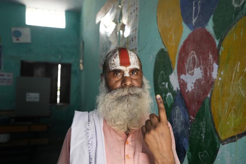 Un religioso hindú indio muestra su dedo marcado con tinta indeleble tras votar en la quinta ronda de unas elecciones nacionales de varias fases ante un centro electoral en Ayodhya, India, el lunes 20 de mayo de 2024. (AP Foto/Rajesh Kumar Singh)