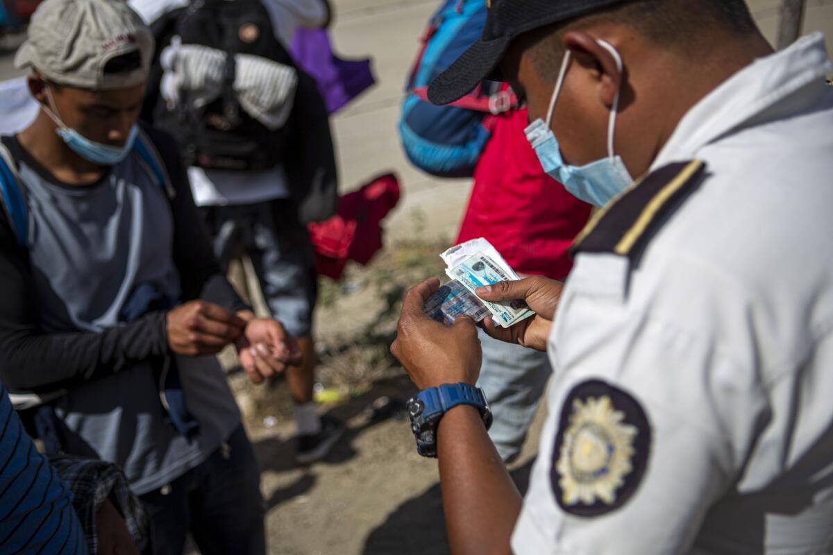 Un policía guatemalteco revisa las identificaciones de migrantes hondureños 