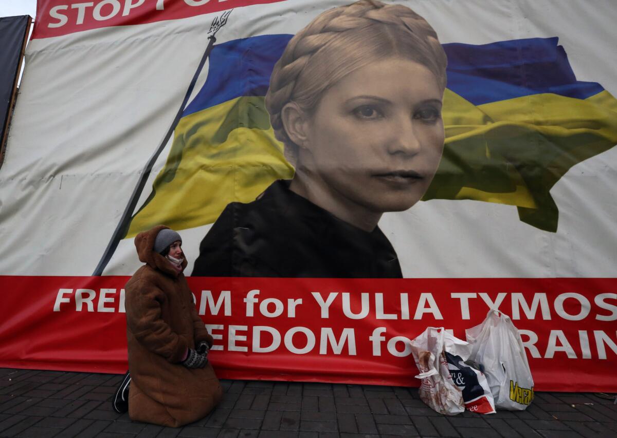 A woman kneels in Independence Square in Kiev, Ukraine, this week in front of a banner showing jailed opposition leader Yulia Tymoshenko.