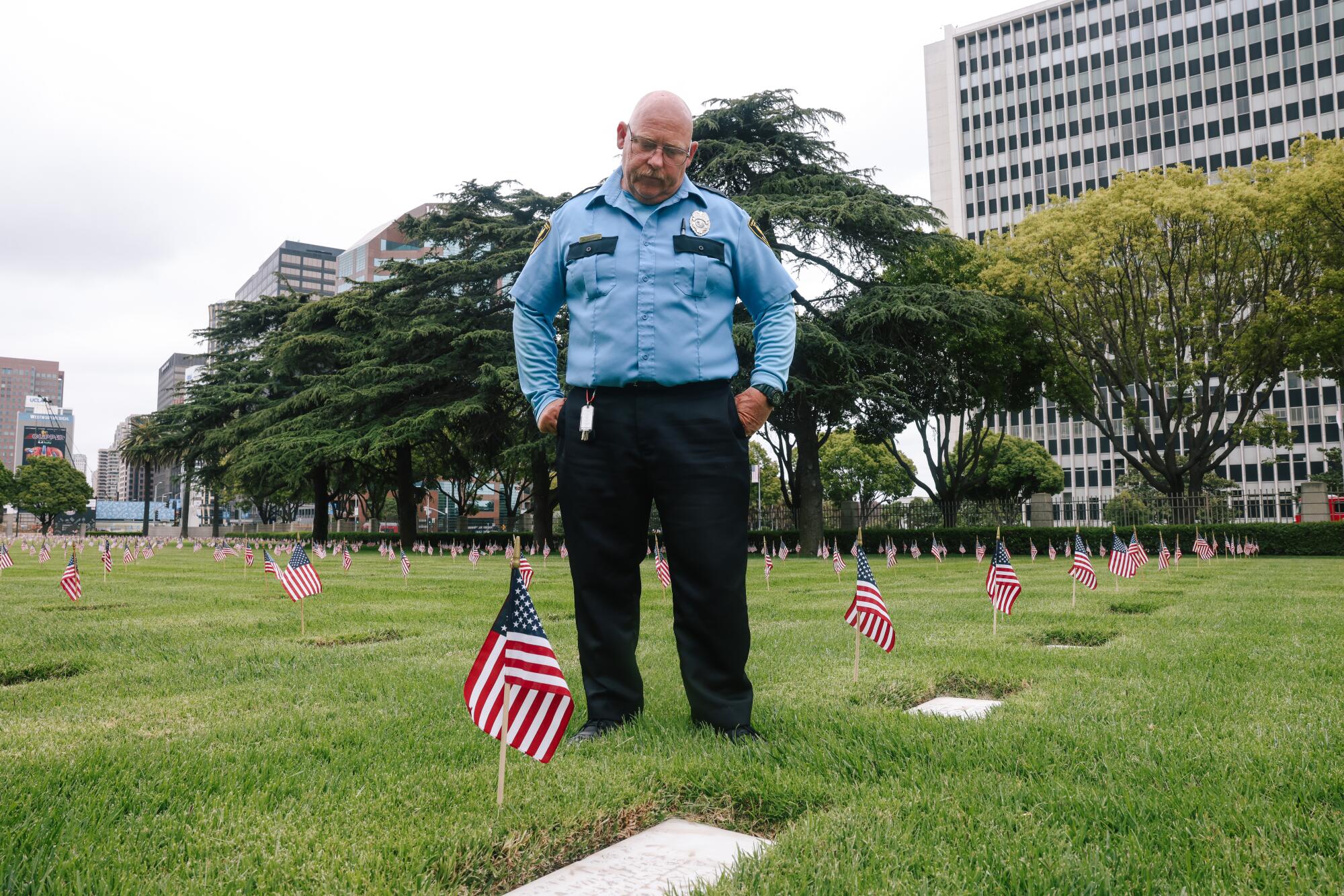 Scott Sargent, who works as security, looks down at the grave of a family member, Lewis L. Owens.