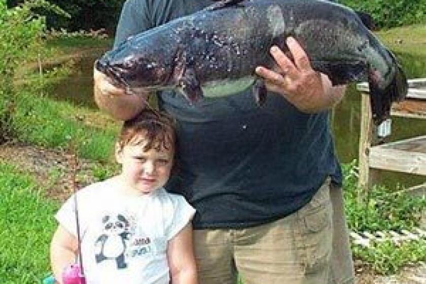 In this undated photo released by the N. C. Wildlife Resources Commission, David Hayes holds his state record-breaking channel catfish while his three-year-old granddaughter Alyssa holds the Barbie rod and reel that Hayes used to reel in the 21-pound, 1 ounce fish in Elkin, N.C.