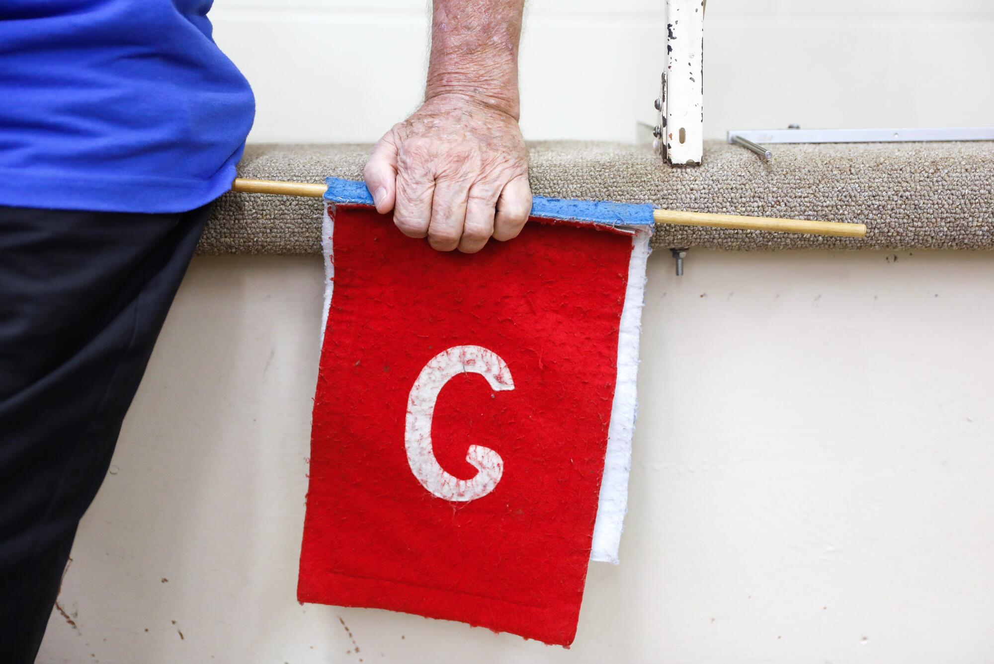 A man has his hand on a red flag with the letter G.