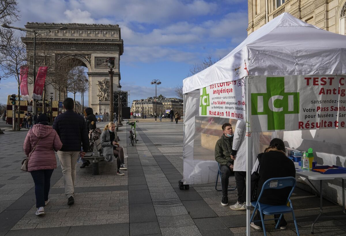 A man gets a nasal swap at a mobile COVID-19 testing site at the Champs Elysees avenue in Paris, Wednesday, Jan. 5, 2022. France is allowing health workers who are infected with the coronavirus but have few or no symptoms to keep treating patients rather than self-isolate, an extraordinary stop-gap measure aimed at alleviating staff shortages at hospitals and other medical facilities caused by an unprecedented explosion in infections. The Arc de Triomphe in the background. (AP Photo/Michel Euler)