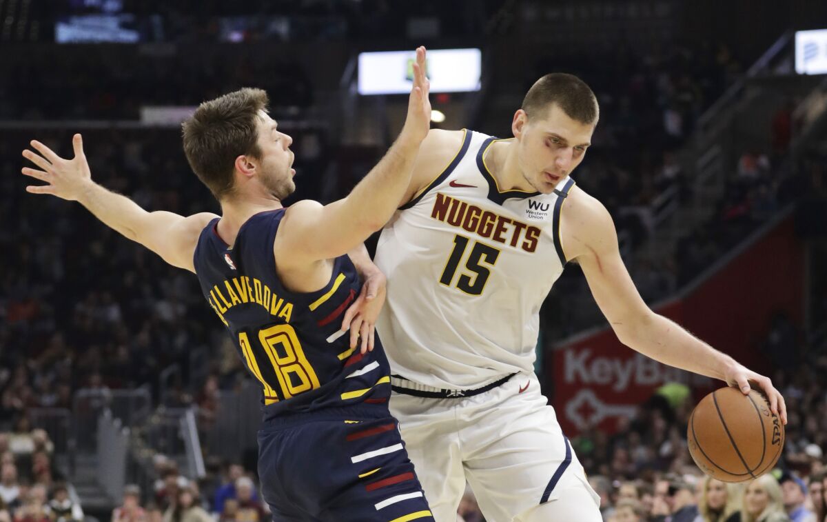 Denver Nuggets' Nikola Jokic (15) drives past Cleveland Cavaliers' Matthew Dellavedova (18) in the second half of an NBA basketball game, Saturday, March 7, 2020, in Cleveland. The Cavaliers won 104-102. (AP Photo/Tony Dejak)