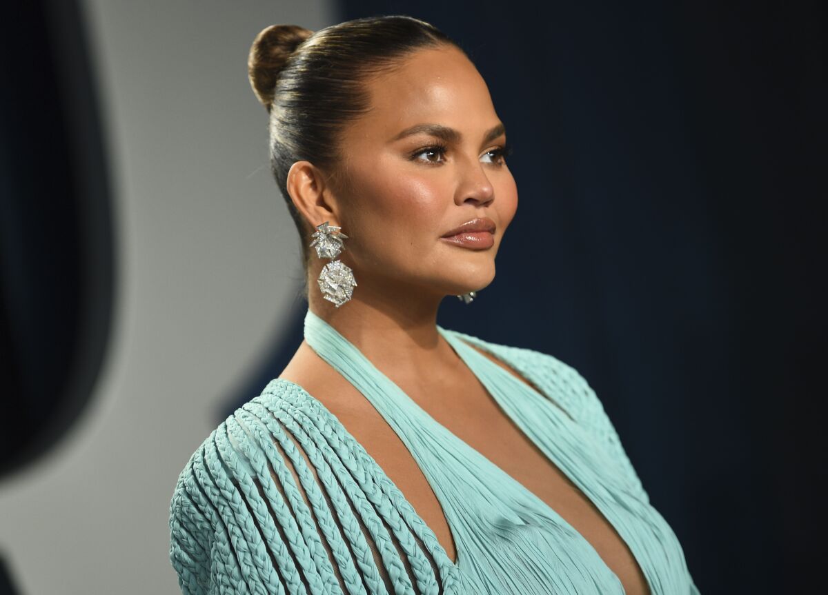 Chrissy Teigen poses in a mint green dress and updo