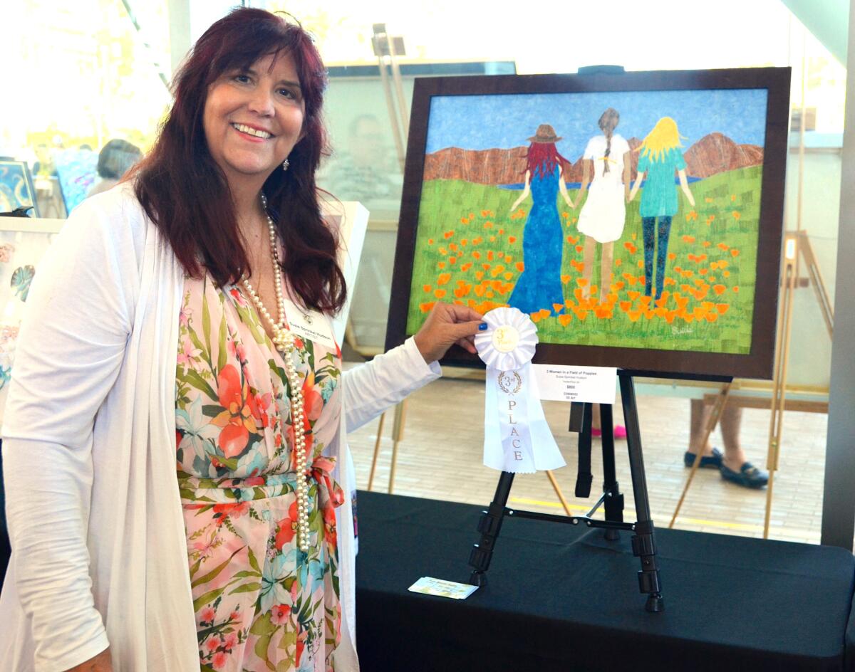 Susie Sprinkel Hudson stands with her third-place ribbon and "3 Women in a Field of Poppies."
